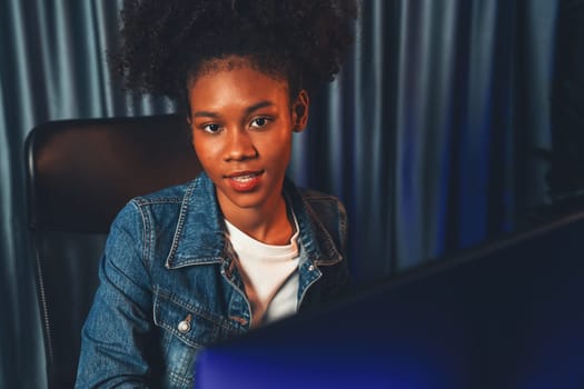 Young African American woman with surprise face, wearing blue jeans shirt and looking at final project document on laptop for planing next sequence. Concept of work at neat home place. Tastemaker.