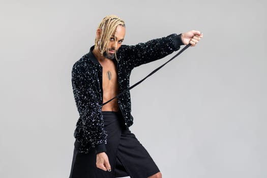 Man wearing women clothing dancing. Brazilian homosexual male wearing black skirt and jacket with sequins posing in photo studio on white background. Bearded gay with make up