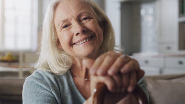 Happy, walking stick and portrait of senior woman on sofa in living room at retirement home. Smile, confident and elderly female person with a disability for hands on cane relaxing in lounge at house.