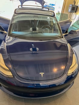 Castle Rock, Colorado, USA-March 14, 2024-A shiny blue Tesla Model 3 sits in the well-kept garage of a single-family house, its sleek design accentuated by the gentle care of a home car wash.