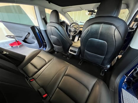 Castle Rock, Colorado, USA-March 14, 2024-The interior of a Tesla Model 3, featuring its premium black seats and modern dashboard, receives a meticulous cleaning in the garage of a private residence.