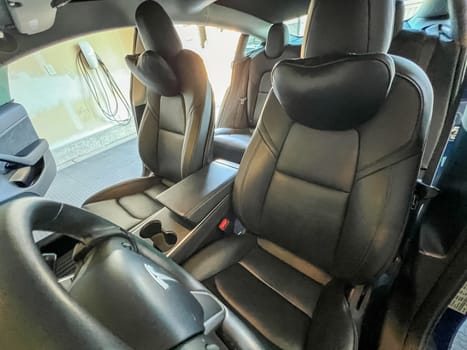 Castle Rock, Colorado, USA-March 14, 2024-The interior of a Tesla Model 3, featuring its premium black seats and modern dashboard, receives a meticulous cleaning in the garage of a private residence.