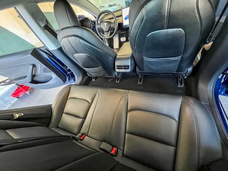 Castle Rock, Colorado, USA-March 14, 2024-The interior of a Tesla Model 3, featuring its premium black seats and modern dashboard, receives a meticulous cleaning in the garage of a private residence.