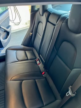 Castle Rock, Colorado, USA-March 14, 2024-The interior of a Tesla Model 3, featuring its premium black seats and modern dashboard, receives a meticulous cleaning in the garage of a private residence.