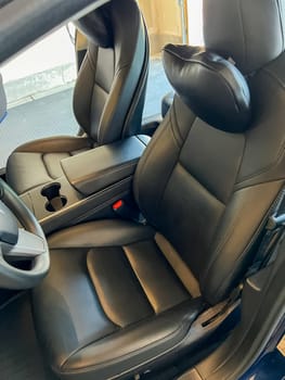 Castle Rock, Colorado, USA-March 14, 2024-The interior of a Tesla Model 3, featuring its premium black seats and modern dashboard, receives a meticulous cleaning in the garage of a private residence.