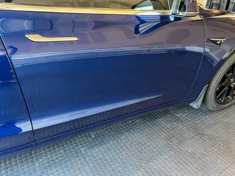 Castle Rock, Colorado, USA-March 14, 2024-A shiny blue Tesla Model 3 sits in the well-kept garage of a single-family house, its sleek design accentuated by the gentle care of a home car wash.