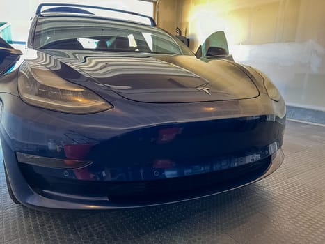 Castle Rock, Colorado, USA-March 14, 2024-A shiny blue Tesla Model 3 sits in the well-kept garage of a single-family house, its sleek design accentuated by the gentle care of a home car wash.