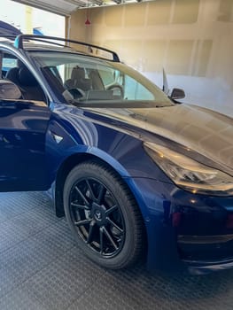 Castle Rock, Colorado, USA-March 14, 2024-A shiny blue Tesla Model 3 sits in the well-kept garage of a single-family house, its sleek design accentuated by the gentle care of a home car wash.