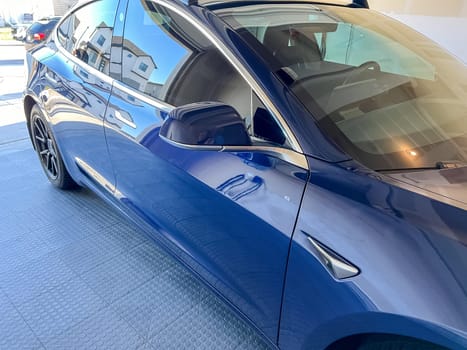 Castle Rock, Colorado, USA-March 14, 2024-A shiny blue Tesla Model 3 sits in the well-kept garage of a single-family house, its sleek design accentuated by the gentle care of a home car wash.