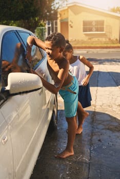 Boy, carwash and vehicle in home, soap and driveway for chores. Siblings, duty and cleaning car for pocket money and responsibility, foam wash and child on weekend for help with task for family.