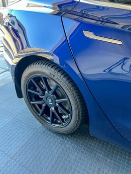 Castle Rock, Colorado, USA-March 14, 2024-A shiny blue Tesla Model 3 sits in the well-kept garage of a single-family house, its sleek design accentuated by the gentle care of a home car wash.