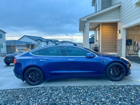 Castle Rock, Colorado, USA-March 14, 2024-A shiny blue Tesla Model 3 sits in the well-kept garage of a single-family house, its sleek design accentuated by the gentle care of a home car wash.