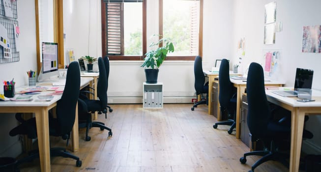 Office, empty and interior for workspace, creative agency or design studio for organisation career. Chairs, desks and laptops for project tasks, research and online assessment with window for decor.