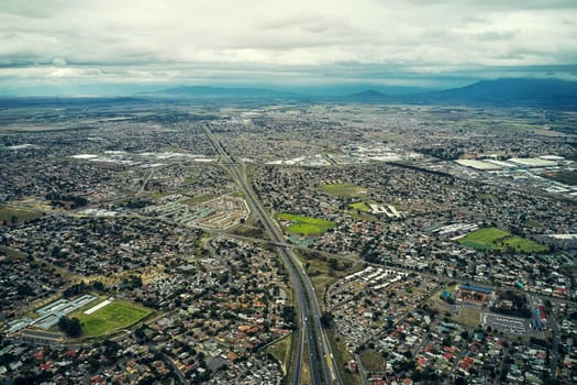 Drone, horizon and city sky with highway, mountains and landscape of buildings with nature. Society, development and travel with neighborhood, street network and aerial view of urban infrastructure.