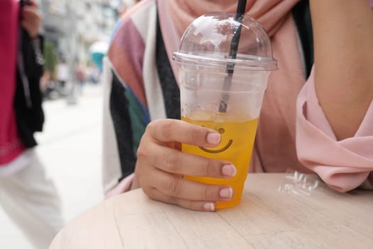 orange juice with ice cube in a plastic container .