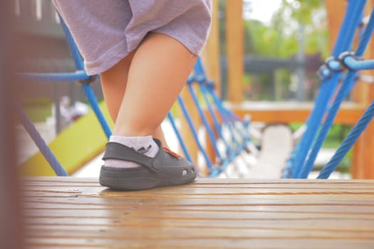 A little girl in pink shoes is standing on a wooden deck,