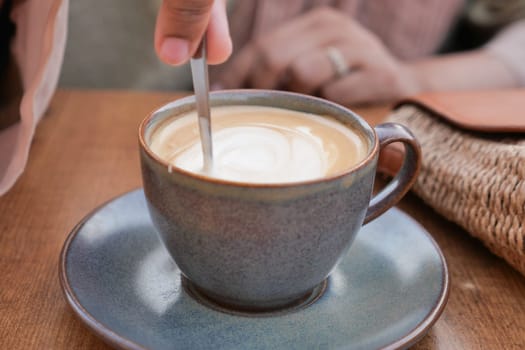 person hand stirring coffee with spoon