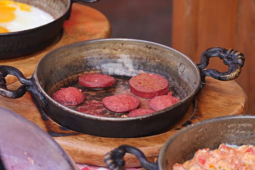 Cooking a dish of breakfast sausage in a pan on a wooden table,