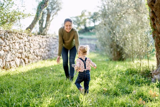 Little girl runs to her mother who opened her arms across the clearing. Back view. High quality photo