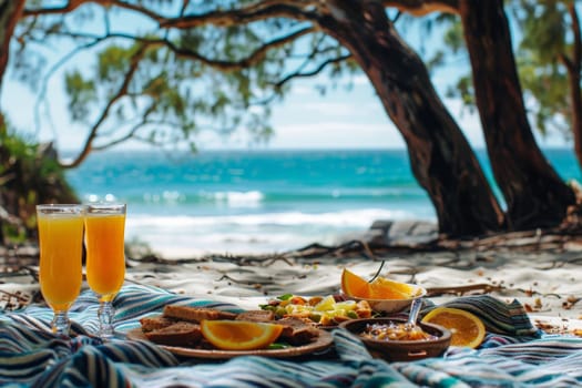 A picnic scene with food and glass of orange juice drink on picnic blanket at beach.