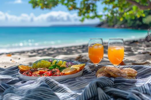 A picnic scene with food and glass of orange juice drink on picnic blanket at beach.