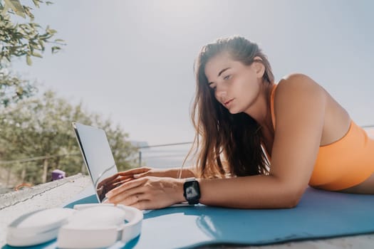 Digital nomad, Business woman working on laptop by the sea. Pretty lady typing on computer by the sea at sunset, makes a business transaction online from a distance. Freelance, remote work on vacation