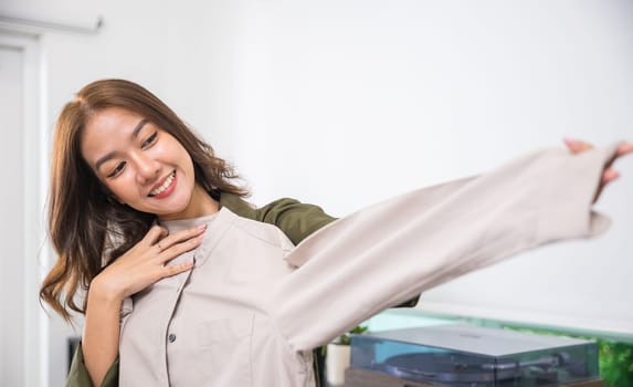 The woman in the image is smiling and appears to be admiring a piece of clothing. She looks happy and satisfied, perhaps pleased with a new purchase or the quality of the garment