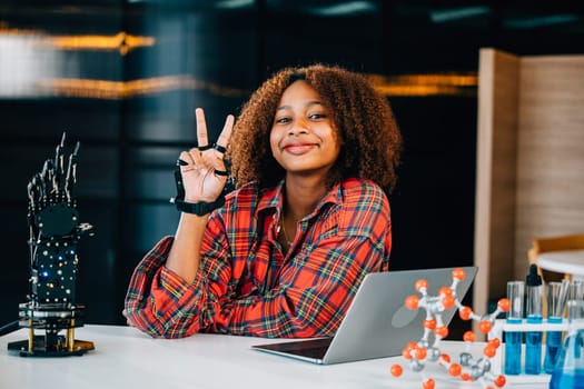 In a classroom setting a Black teenage student explores a robotic arm engaging in learning subjects of interest. Embracing innovation and technology for skill development and joy in education.