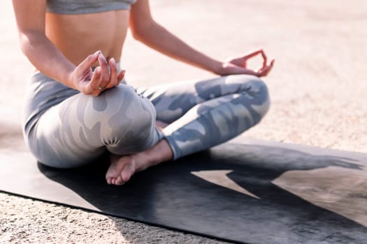 detail of the crossed legs of a woman doing meditation sitting on a yoga mat, concept of mental relaxation and healthy lifestyle