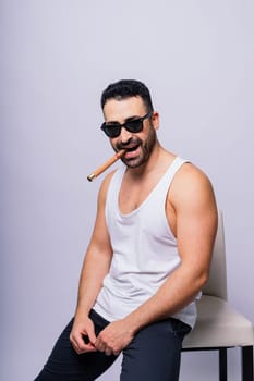 Young man with beard smoking a cigar in a studio