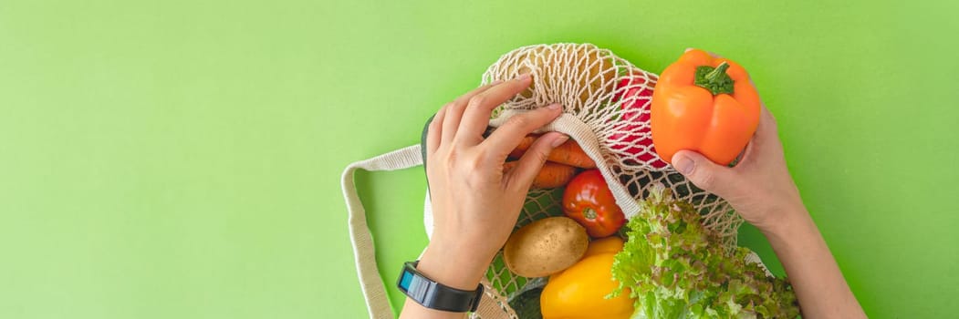 banner of top view of a woman's hands taking vegetables out of an eco-bag. tomatoes, cucumbers, bell peppers and lettuce in a reusable bag. The concept of recycling, respect for nature. flat lay, copy space.