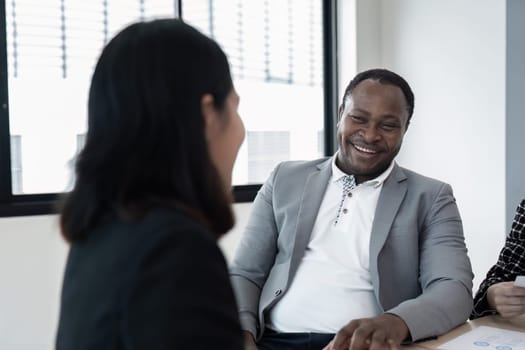 Happy business woman listening to discussion in office boardroom. Diverse business people laughing during meeting in office.