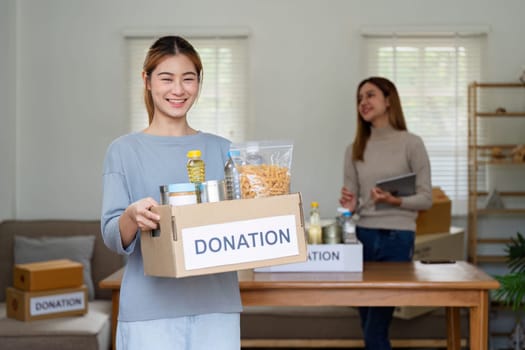 charity, donation and volunteering concept. Volunteer prepare foodstuff box containing food to donate to people poor, disaster victim at home.