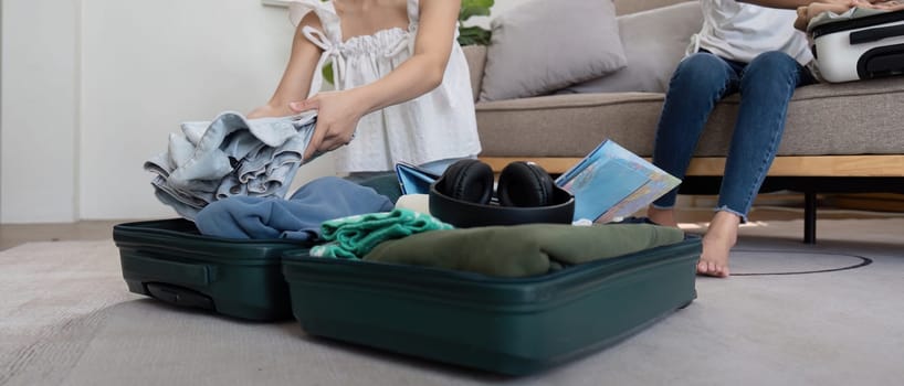 Friends and travel. Two asian young woman friends packing a travel bag before going on holidays.