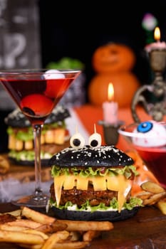 Monster Burger. Black bun, juicy beef cutlet, lettuce, onion, tomato and cheese in the shape of teeth, mozzarella eyes with olives. Definitely a pick-me-up and a perfect Halloween party appetizer.