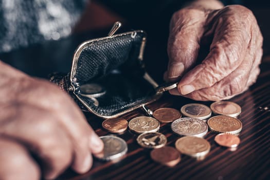 Detailed closeup photo of elderly 96 years old womans hands counting remaining coins from pension in her wallet after paying bills. Unsustainability of social transfers and pension system