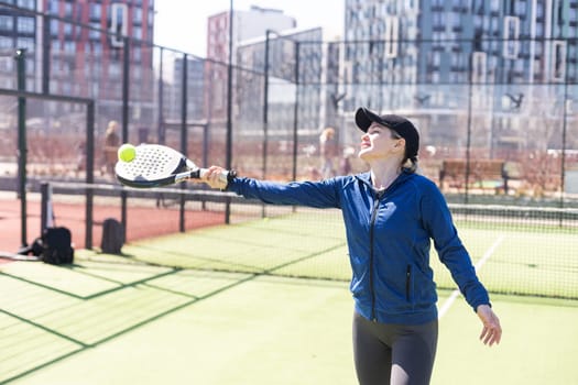 Determined sporty young woman playing padel in court. High quality photo