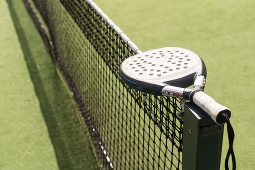 Padel racket and padel ball on a green court in the sunset. High quality photo