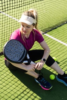 Active young woman trying to beat the ball by Padel racket while playing tennis in the court. High quality photo