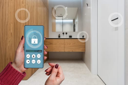 Smart home automation app on smartphone hold by female hand with home interior in background.
