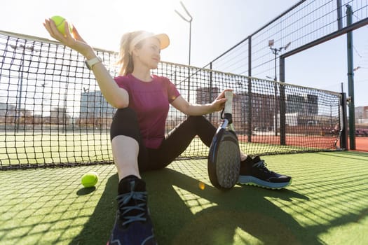 Happy female paddle tennis player during practice on outdoor court looking at camera. Copy space. High quality photo