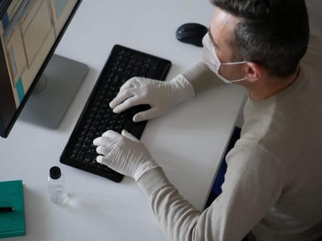 Young woman wearing protective gloves on hands and mask on face working from office or home using laptop on desk. Preventing corona virus covid-19 spread during epidemic outbreak. top view from above