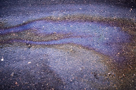 Abstract background from motor oil, gas or petrol spilled on asphalt.
