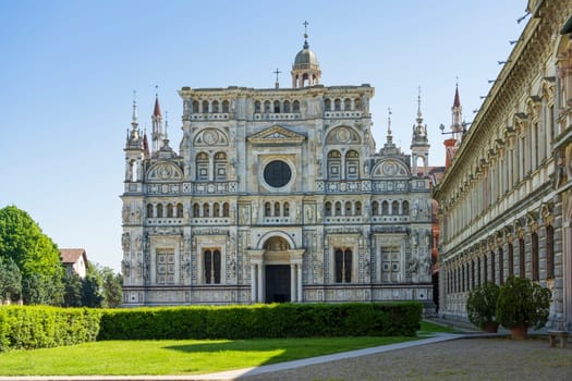 Certosa di Pavia monastery, historical monumental complex that includes a monastery and a sanctuary. green court and a church.The Ducale Palace on the right,Pavia,Italy.