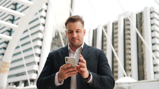 Caucasian business man checking mobile phone and looking report sales from marketing team while standing at urban city. Skilled manager working on mobile phone and looking at data analysis. Urbane.