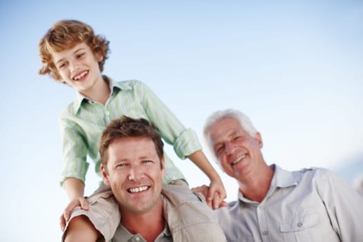 Portrait of grandfather, father and child by blue sky for bonding, relationship and relax together. Family, generations and grandpa, dad and young boy on shoulders for holiday, vacation and weekend.
