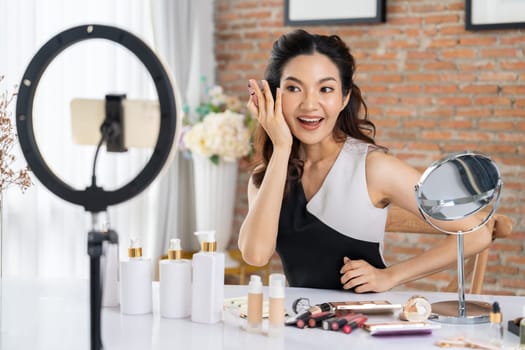 Woman influencer shoot live streaming vlog video review makeup uttermost social media or blog. Happy young girl with cosmetics studio lighting for marketing recording session broadcasting online.