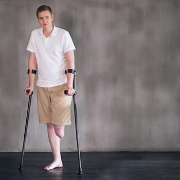 Portrait, crutches and man with disability in healthcare centre for walking, muscle strength and medical for support. Amputee, exercise and physiotherapy for physical therapy with rehabilitation.