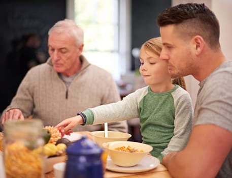 Family, breakfast and kid eating food in home together for bonding with father in the morning. Cereal, parents and grandfather with child at table with pineapple, fruit and nutrition for healthy diet.