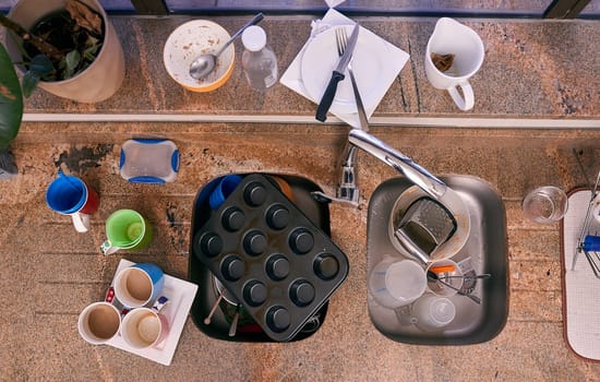 Top view, dirt and kitchen with dishes, chaos and knife on counter on a background in home for chores. Above, sink and unclean utensils, baking and garbage mess with glass cups in water for housework.